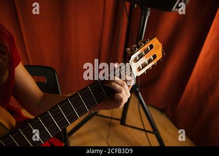 Crop main de femme artistique méconnaissable en robe rouge jouant un morceau de guitare sur scène en Espagne Banque D'Images