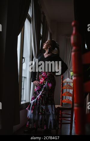 Femme danseuse en costume pour le flamenco assis et regarder dehors fenêtre Banque D'Images