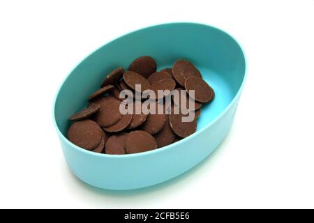 Boutons chocolat au lait dans un récipient bleu sur fond blanc Banque D'Images