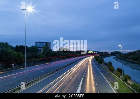 Des pistes lumineuses de voitures roulant sur une autoroute britannique avant aube Banque D'Images