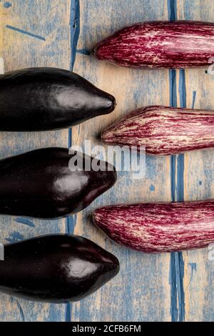 Ensemble d'aubergines fraîches et mûres placées près d'un morceau de rayures tissu sur un plan d'examen en bois abîmé Banque D'Images