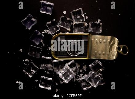 Depuis le dessus de l'appareil photo rétro placé dans une bole métallique sur une surface noire avec des glaçons dispersés démontrant le concept de gadget bien conservé Banque D'Images