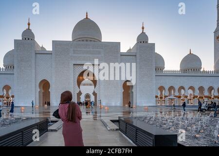 Femme en hijab regardant une mosquée au coucher du soleil | Mosquée cheik Zayed d'Abu Dhabi | magnifique architecture islamique | Attraction touristique Banque D'Images