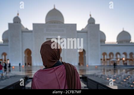 Femme en hijab regardant une mosquée au coucher du soleil | Mosquée cheik Zayed d'Abu Dhabi | magnifique architecture islamique | Attraction touristique Banque D'Images