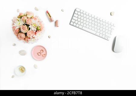 Bureau pour femmes stylisé, bureau. Espace de travail avec, ordinateur portable, roses, presse-papiers. Accessoires de mode pour femmes sur fond blanc. Flat Lay vue de dessus Banque D'Images