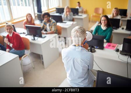 Une femme parle au mégaphone en salle de classe, vue arrière Banque D'Images