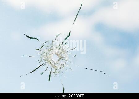 Trou de balle dans le verre contre l'arrière-plan du ciel, gros plan Banque D'Images