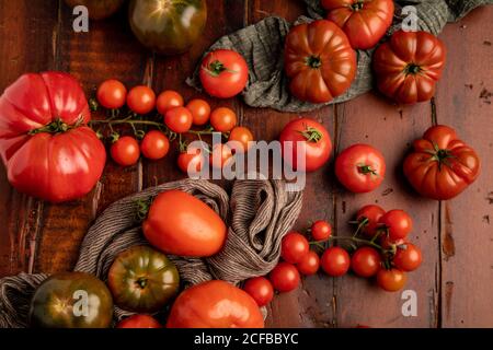 Ensemble de tomates fraîches assorties et serviettes en tissu placées dessus table en bois dans la cuisine Banque D'Images