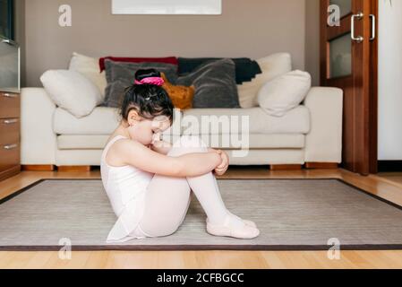 S'ennuient une petite fille tristes pensive en léopard et collants assis sur le sol et en se reposant pendant la répétition de ballet à accueil Banque D'Images