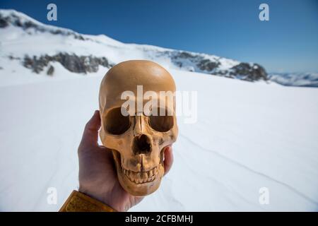 L'homme tient le crâne humain, artefact en paysage d'hiver. Banque D'Images