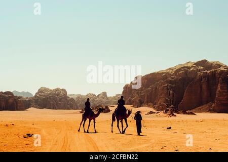 Les touristes voyagent en chameaux avec un guide bédouin à Wadi Rum, en Jordanie Banque D'Images