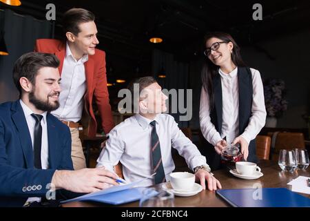 Femme d'affaires qui verse du thé au travail Banque D'Images