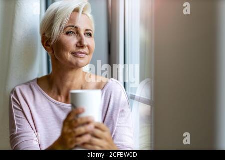 Femme détendue à la maison assis à la fenêtre Banque D'Images