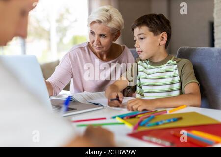 Mère aidant ses enfants à faire leurs devoirs à la maison Banque D'Images