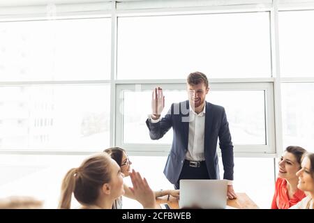 Camarades de classe femmes et hommes célébrant l'examen de mathématiques de la pathing, se sentant excitant et gai , donnant élevé cinq pendant la réunion informelle en amical Banque D'Images