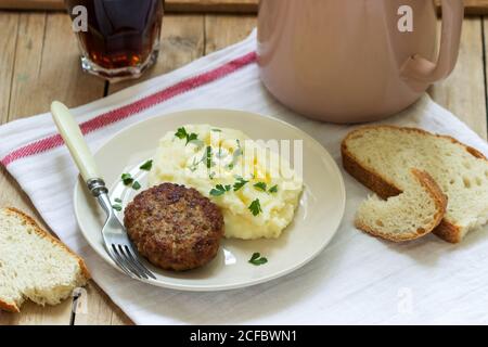 Côtelette, purée de pommes de terre avec beurre et persil et thé sur une table en bois. Banque D'Images