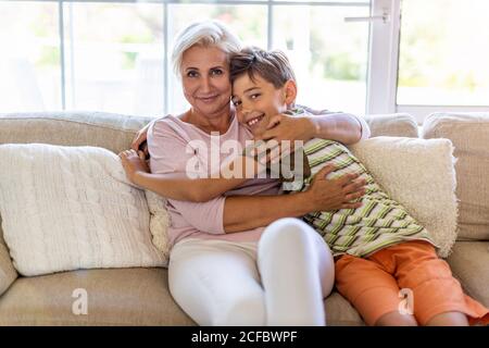 Mère et fils heureux qui s'embrasent sur le canapé Banque D'Images
