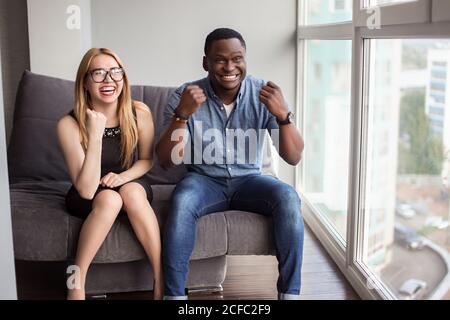 Couple interracial sur la date vue par la fenêtre de café - afro homme américain utilisant le téléphone et l'expression du visage de petite amie asiatique dans Amour - joyeux mélange Banque D'Images