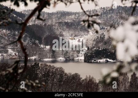 Vallée rurale pittoresque et vallonnée avec de la neige couvrant les arbres et le rivage De lac en jour sombre en Norvège Banque D'Images