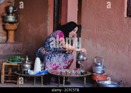 Berbère femme préparant et versant du thé à la menthe marocaine Banque D'Images