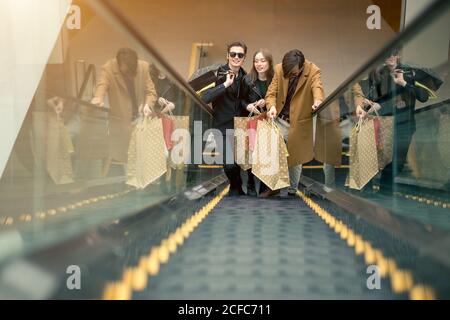 Trois copines sur escalator with shopping bags Banque D'Images