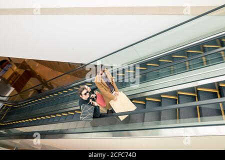 Trois copines sur escalator with shopping bags Banque D'Images