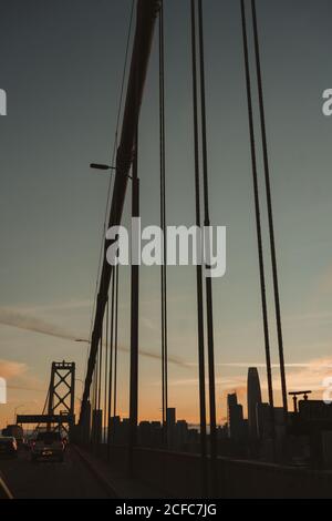 Célèbre pont suspendu de la baie de San Francisco avec des voitures en mouvement contre le ciel nuageux au lever du soleil Banque D'Images