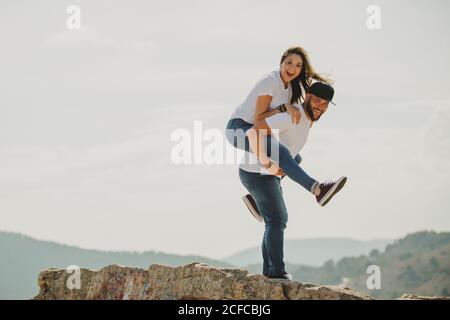 Charmant homme tenant une femme sur le dos à la falaise de montagne Banque D'Images