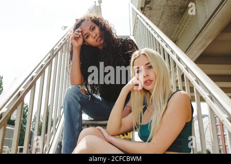 De belles jeunes femmes assises dans les escaliers le jour ensoleillé de l'été À Berlin, en regardant la caméra Banque D'Images