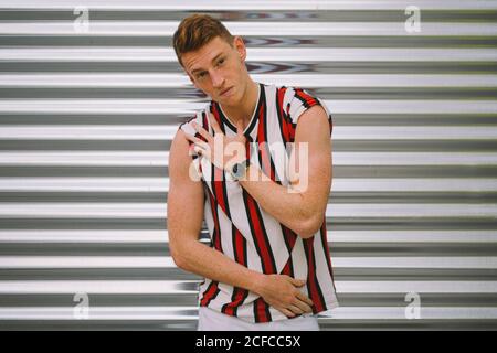 Beau homme heureux pendu sur la porte de garage en acier regardant appareil photo Banque D'Images