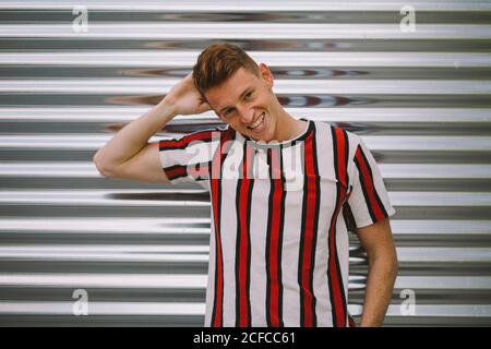 Beau homme heureux pendu sur la porte de garage en acier regardant appareil photo Banque D'Images