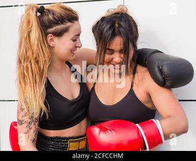 Vue latérale des femmes fières multiethniques ravies portant un soutien-gorge de sport enserrer après l'entraînement dans la rue Banque D'Images