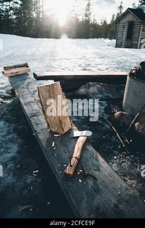 Feu de camp et feu de bois avec hache placé près de la petite cabine de bûcherons dans la forêt enneigée en hiver dans la campagne De Finlande Banque D'Images