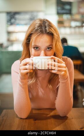 Jeune femme ayant une tasse de café à table dans le café Banque D'Images