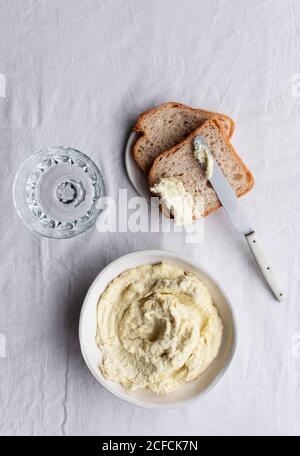 De dessus bol avec codfish brandade placé près des olives, des tranches de pain et des feuilles de baie sur une table de cuisine fond blanc Banque D'Images