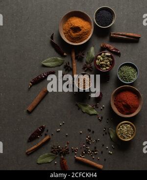 Composition vue de dessus avec différents types d'épices aromatiques naturelles placé sur fond gris foncé Banque D'Images