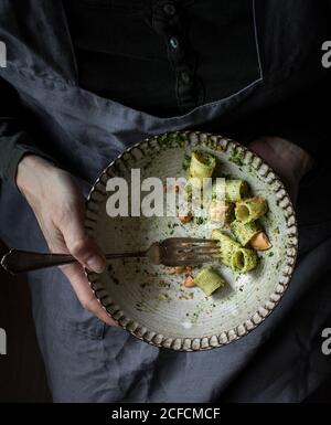 Anonyme femme tenant un bol de pâtes pacheri avec du pesto de chou frisé frais et des arachides moulées Banque D'Images