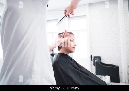 Coiffeur coupe les cheveux de la femme avec des ciseaux Banque D'Images