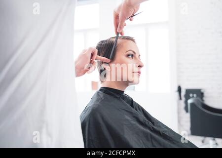 Coiffeur coupe les cheveux de la femme avec des ciseaux Banque D'Images