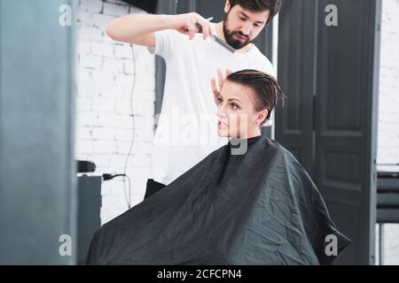 Coiffeur coupe les cheveux de la femme avec des ciseaux Banque D'Images