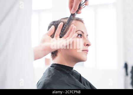 Coiffeur coupe les cheveux de la femme avec des ciseaux Banque D'Images