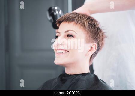 Coiffeur séchage des cheveux à la femme Banque D'Images