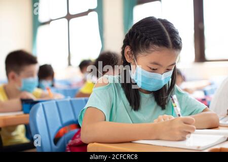 les élèves portant un masque et étudiant en classe. Banque D'Images