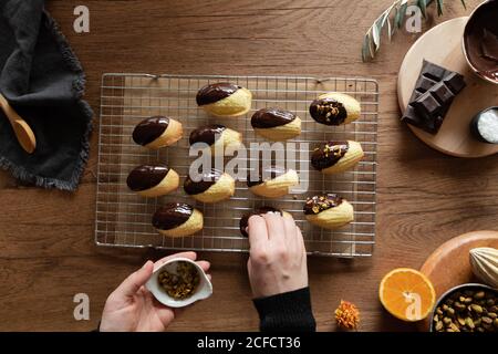 Vue de dessus des mains de récolte de la femme de ménage saupoudrer maison trempée En biscuits de Madeleine au chocolat avec noix à la table en bois Banque D'Images