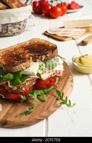 Légumes frais et fromage placés au milieu de tranches de pain frit avec jambon sur table blanche Banque D'Images