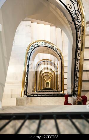 Depuis le dessus de l'escalier en colimaçon en pierre légère avec du métal ornemental banister dans le vieux bâtiment de Madrid avec personne méconnaissable debout sur les escaliers Banque D'Images