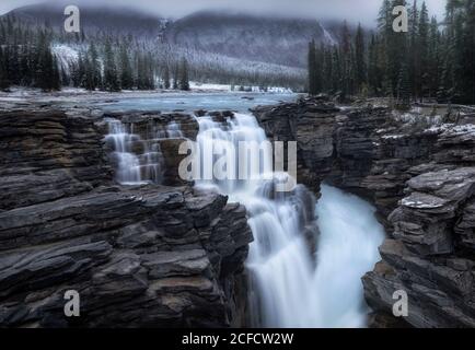 Paysage spectaculaire avec belle cascade de cascade parmi les montagnes rocheuses couvertes Avec forêt de conifères et neige au Canada Banque D'Images