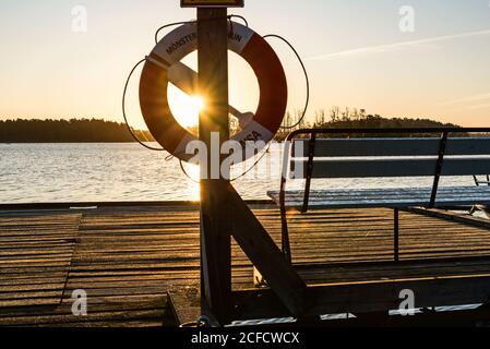 Le soleil du soir brille à travers une bouée de sauvetage suspendue sur une jetée Banque D'Images