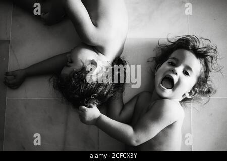 photo en noir et blanc de deux petites sœurs en cure jouant les uns avec les autres tout en roulant sur le sol Banque D'Images