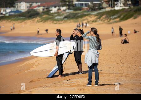 Surfeur d'homme avec des amis sur la plage de Narrabee Nord à Sydney, Nouvelle-Galles du Sud, Australie Banque D'Images